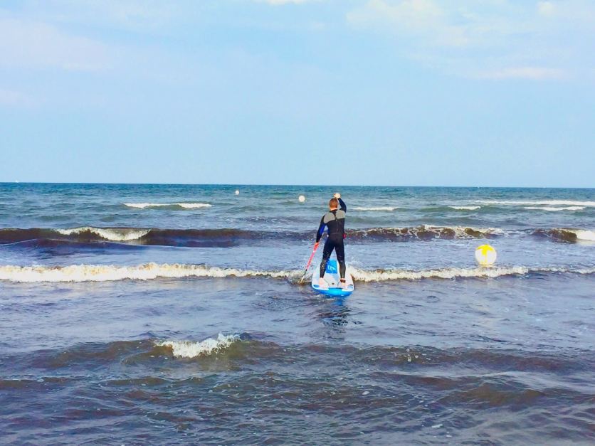 Mit dem SUP-Board in die Wellen der Ostsee: Im Herbst kann man mit etwas Glück sogar sein Paddel am Strand lassen und Wellen reiten. Foto: Luisa Praetorius