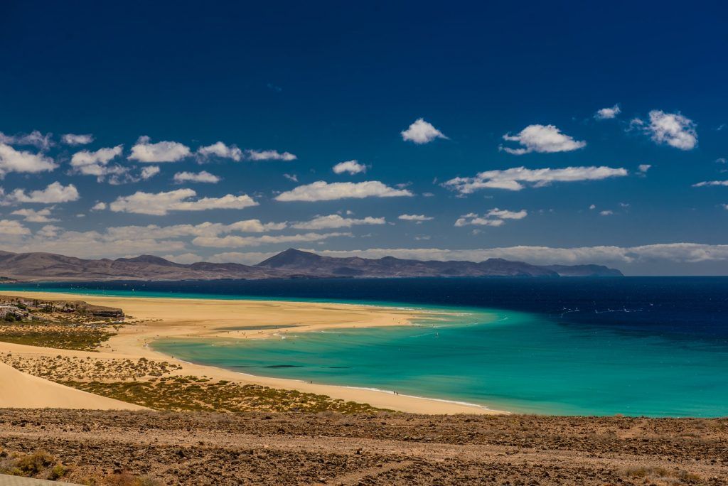 Auf Fuerteventura könnt Ihr endlose Sandstrände entdecken – und mit einem Surfbrett in die Wellen eintauchen. Foto: Unsplash